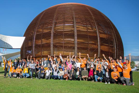 A group of people smiling and waving outside Cern's Dome building
