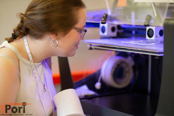 A member of Pier 12 inspecting the progress of a 3D printer